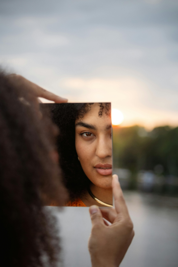 Mulher madura segurando um espelho ao entardecer, em expressão de lucidez